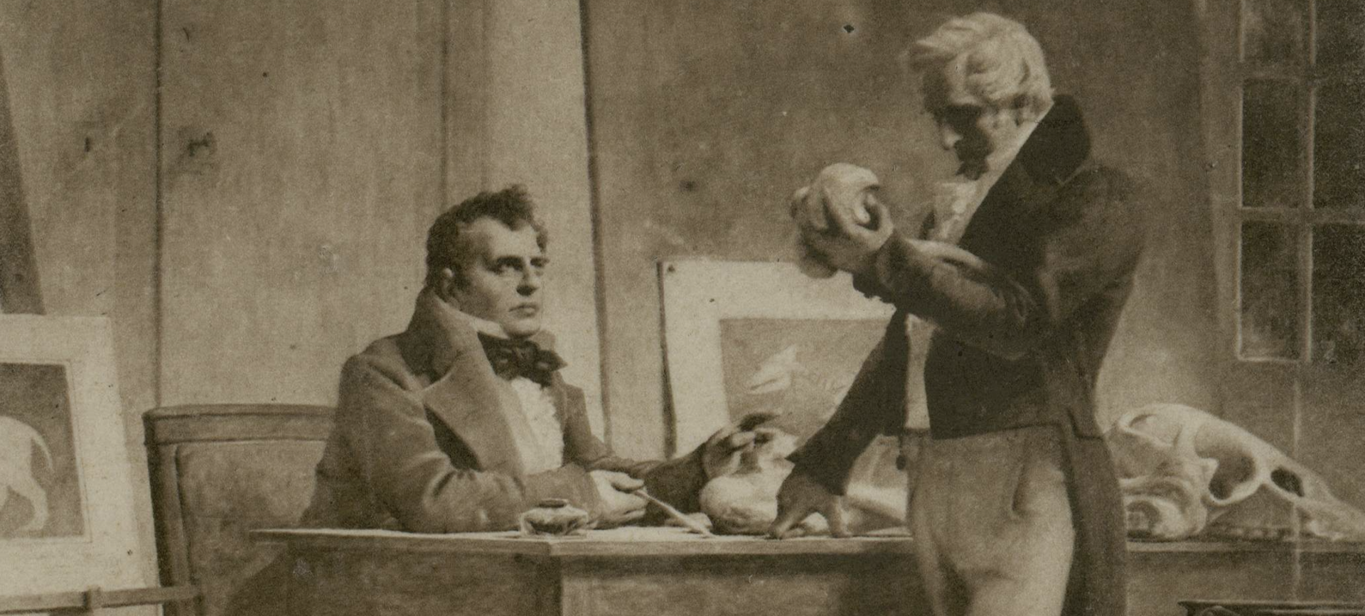 Painting of two men at desk examining fossils